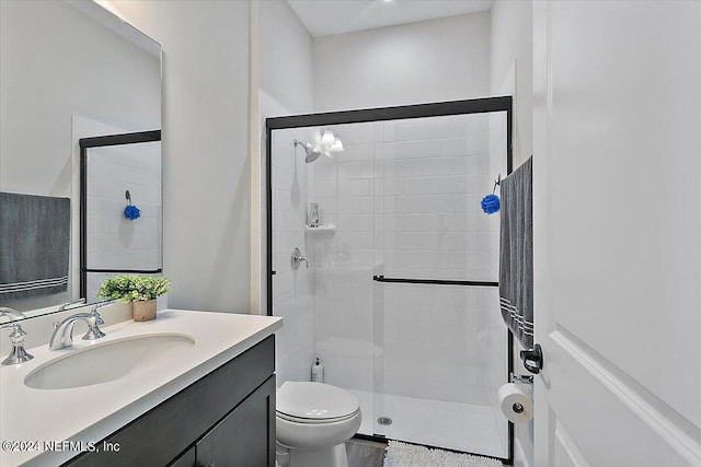 bathroom with toilet, a shower with shower door, and large vanity