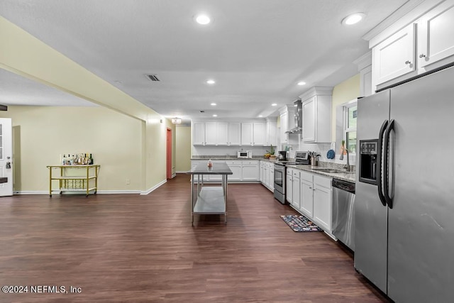 kitchen with white cabinets, appliances with stainless steel finishes, and wall chimney range hood