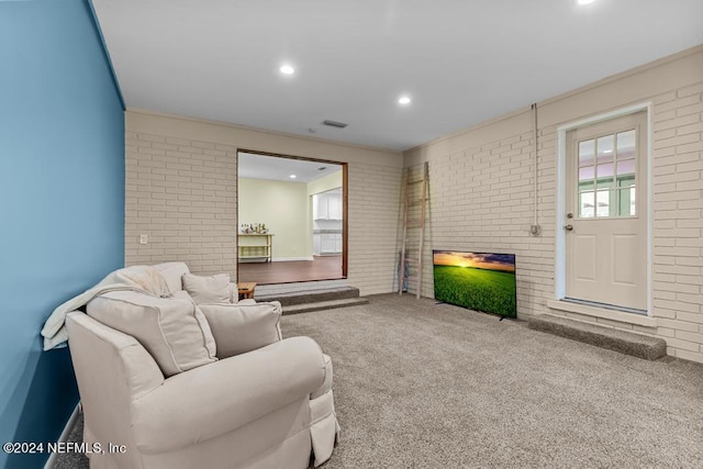 carpeted living room with brick wall and crown molding