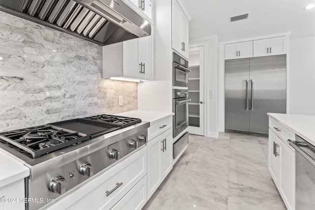 kitchen featuring range hood, white cabinets, appliances with stainless steel finishes, and decorative backsplash