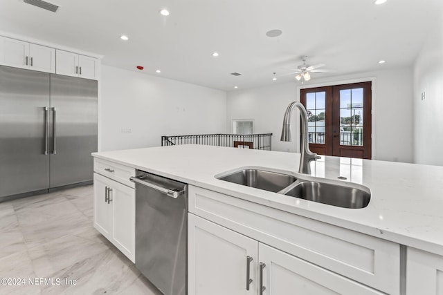 kitchen featuring light stone counters, stainless steel appliances, white cabinetry, sink, and ceiling fan