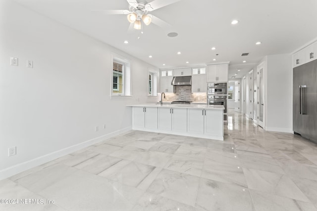 kitchen featuring white cabinetry, backsplash, kitchen peninsula, sink, and ceiling fan