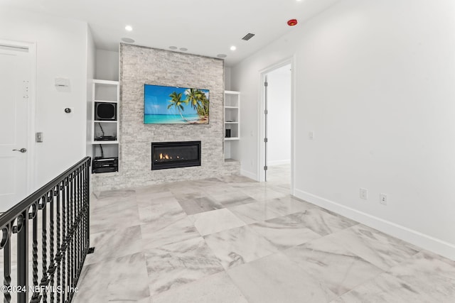 unfurnished living room featuring built in shelves and a stone fireplace