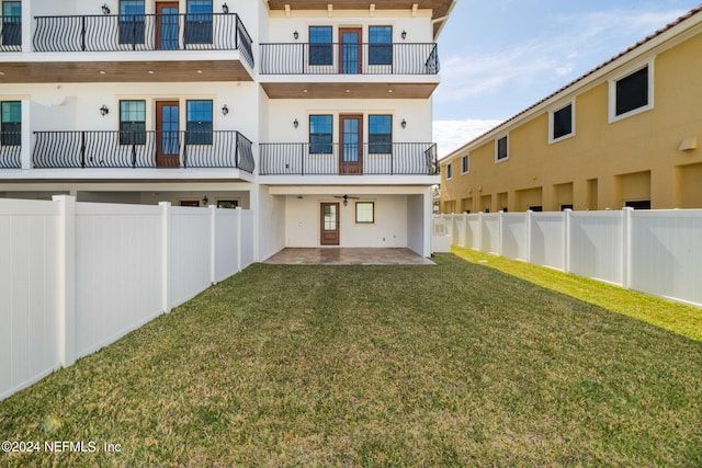 rear view of house with a balcony, a lawn, and a patio area