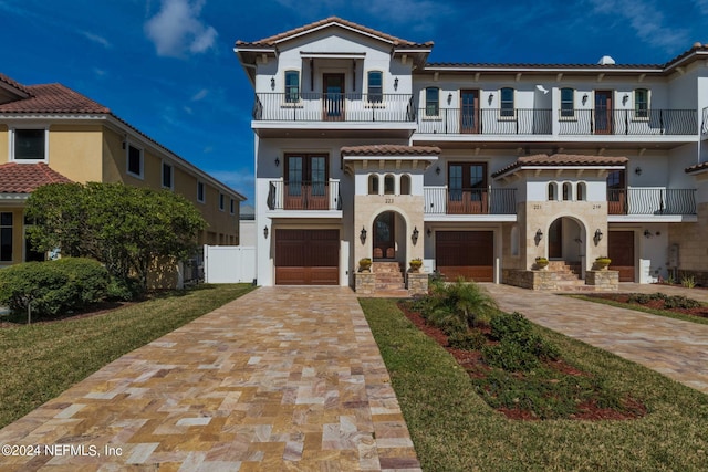 mediterranean / spanish home featuring a balcony, a front yard, and a garage