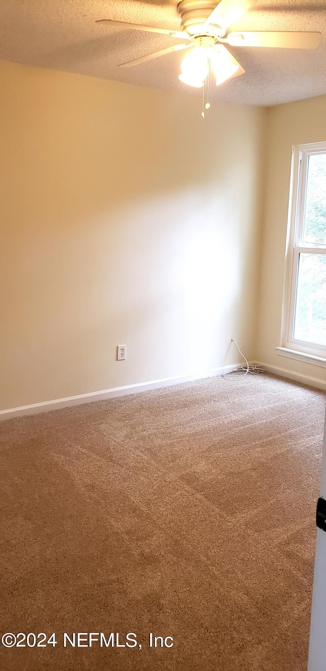 carpeted spare room featuring ceiling fan and a textured ceiling