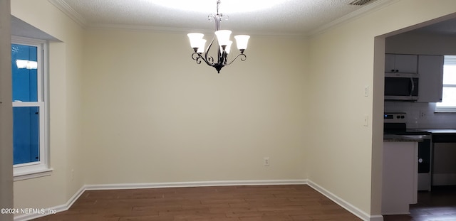 unfurnished dining area featuring a notable chandelier, crown molding, and dark wood-type flooring