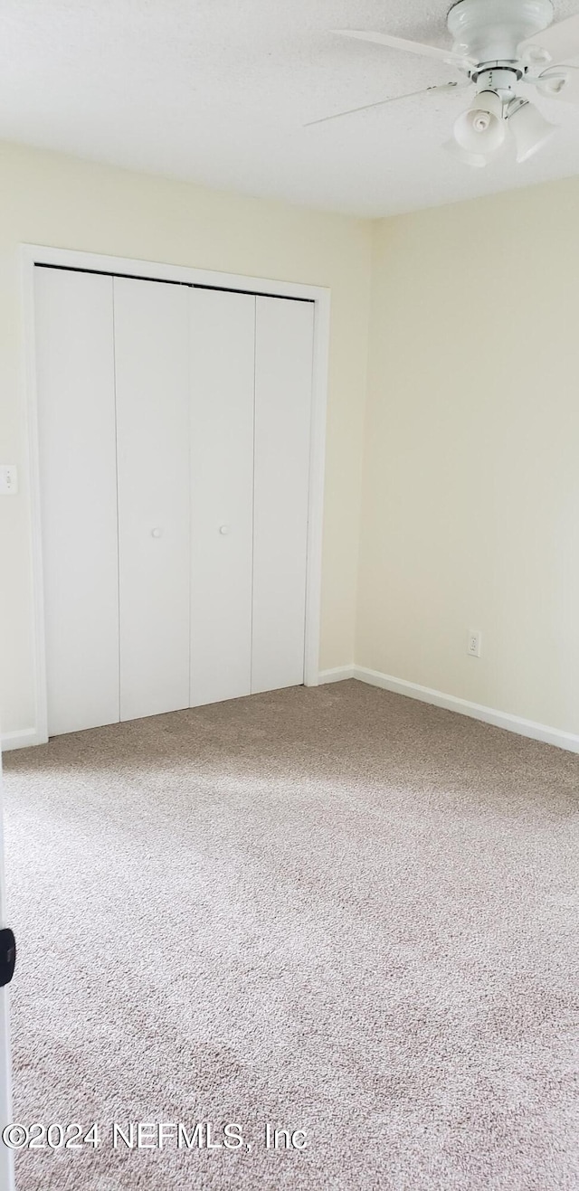 unfurnished bedroom featuring a closet, light carpet, and ceiling fan