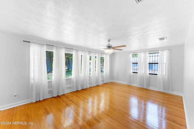 spare room with ceiling fan, light hardwood / wood-style floors, and a textured ceiling