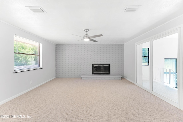 unfurnished living room with ceiling fan, light colored carpet, brick wall, and a brick fireplace