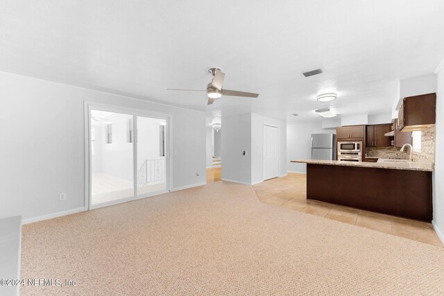 unfurnished living room with light colored carpet, ceiling fan, and sink