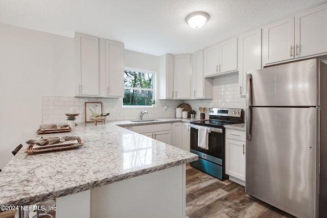 kitchen with backsplash, stainless steel appliances, white cabinetry, and dark hardwood / wood-style flooring