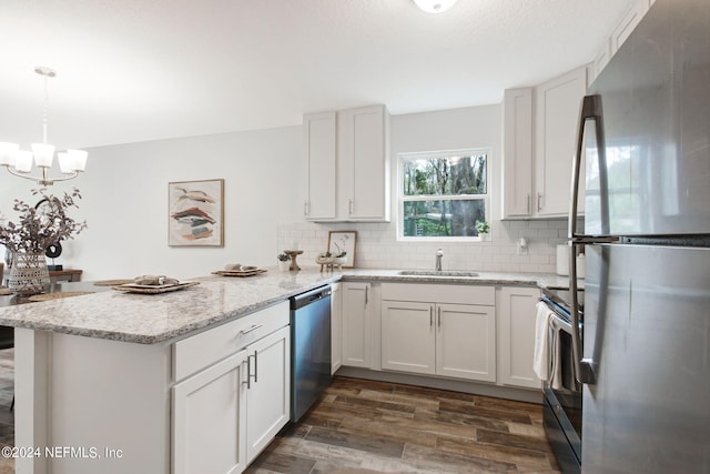 kitchen with dark hardwood / wood-style floors, appliances with stainless steel finishes, a chandelier, backsplash, and decorative light fixtures