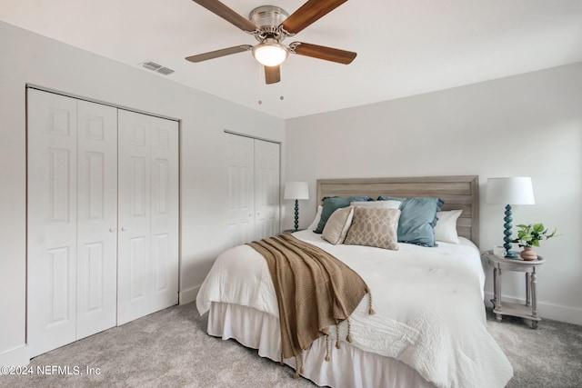 carpeted bedroom with ceiling fan and two closets