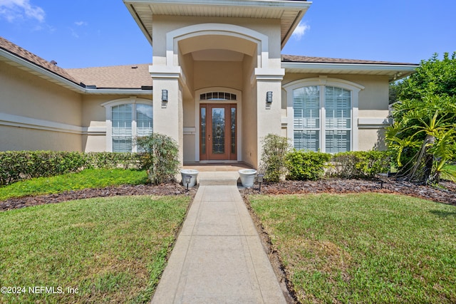 doorway to property with french doors and a lawn