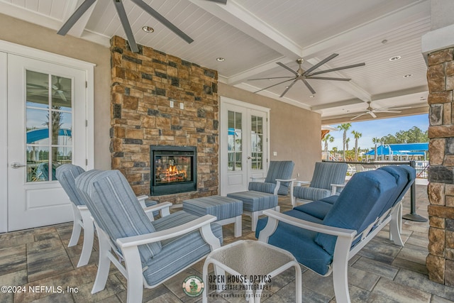 view of patio featuring french doors, an outdoor stone fireplace, and ceiling fan