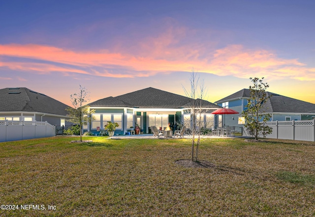 rear view of house featuring a patio area, a lawn, and a fenced backyard