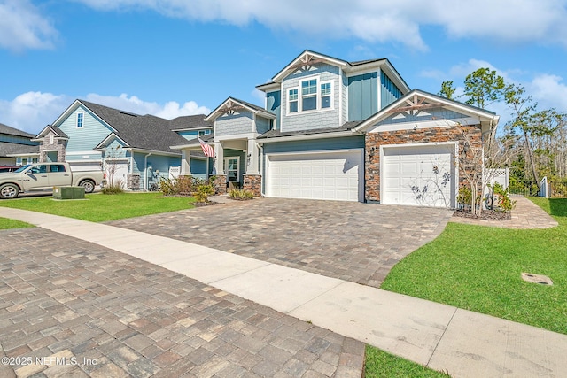 view of front of property with a front yard, decorative driveway, board and batten siding, and stone siding