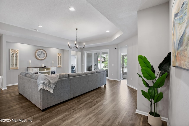 living room with baseboards, recessed lighting, an inviting chandelier, dark wood-style floors, and a raised ceiling