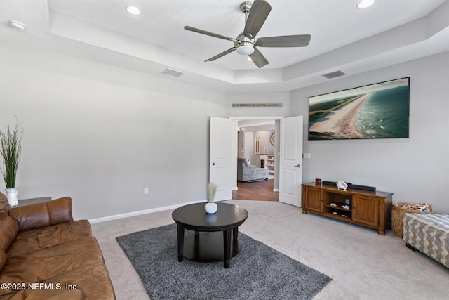 living area featuring a tray ceiling, baseboards, visible vents, and carpet flooring