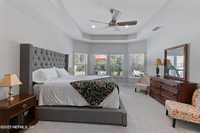 bedroom featuring visible vents, a raised ceiling, multiple windows, and carpet flooring