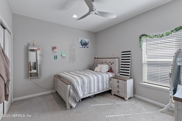 bedroom featuring a ceiling fan, baseboards, a closet, and light carpet