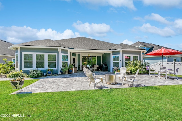 back of property featuring a yard, fence, a shingled roof, and a patio area