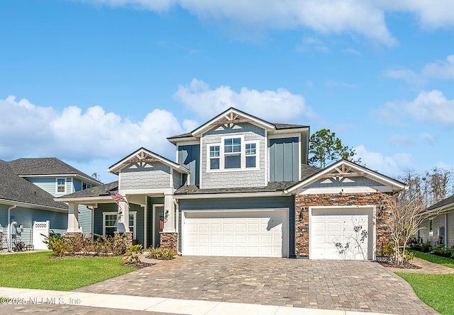 view of front facade featuring decorative driveway, stone siding, board and batten siding, and a front yard