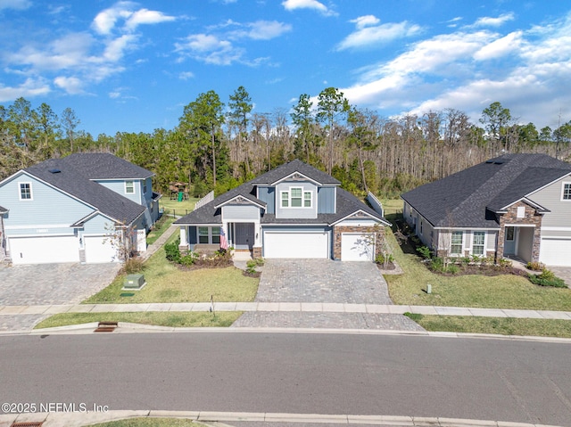 traditional home featuring a front lawn, decorative driveway, stone siding, and an attached garage