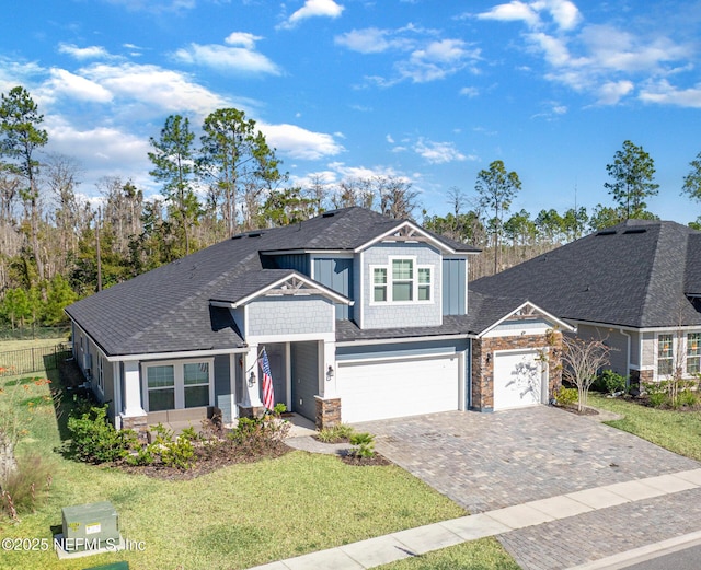 view of front of house with stone siding, decorative driveway, a front yard, and fence