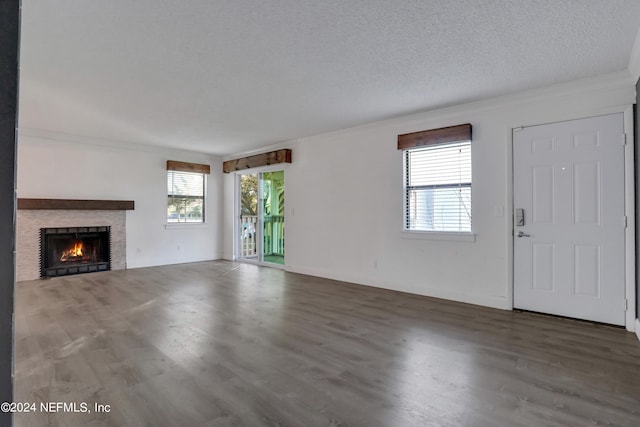 unfurnished living room with a textured ceiling, dark hardwood / wood-style floors, and ornamental molding