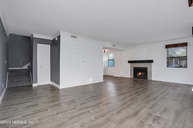 unfurnished living room with a textured ceiling, crown molding, and hardwood / wood-style flooring