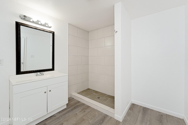 bathroom featuring vanity with extensive cabinet space, wood-type flooring, and tiled shower