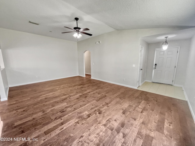 unfurnished living room with visible vents, arched walkways, a ceiling fan, baseboards, and wood finished floors