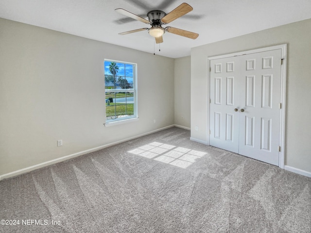 unfurnished bedroom with carpet floors, a closet, baseboards, and a ceiling fan