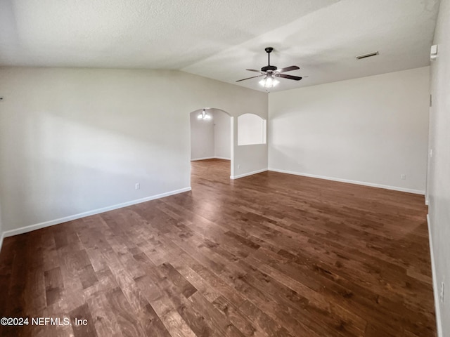 spare room with arched walkways, dark wood-style flooring, visible vents, a ceiling fan, and baseboards