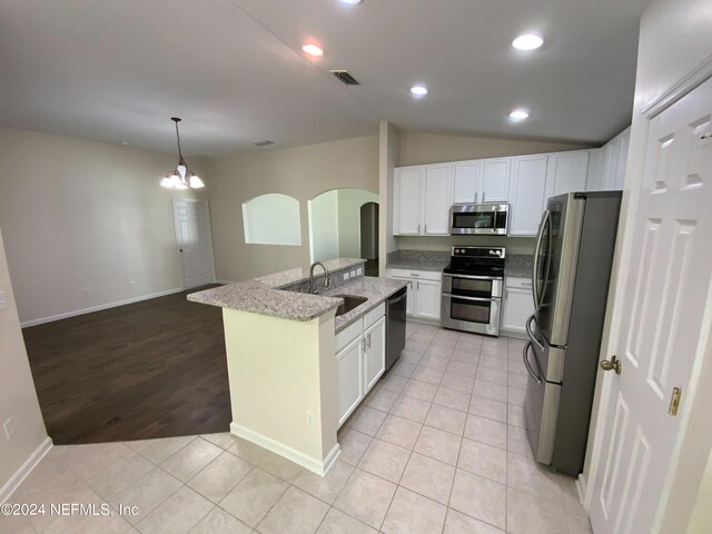 kitchen featuring appliances with stainless steel finishes, lofted ceiling, white cabinetry, light tile patterned floors, and sink