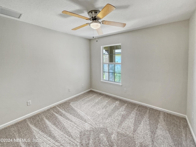 empty room featuring visible vents, attic access, a ceiling fan, carpet flooring, and baseboards