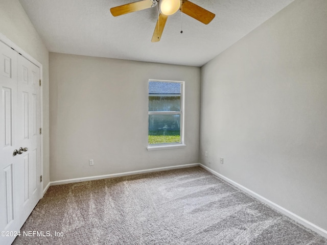 carpeted empty room featuring a ceiling fan and baseboards