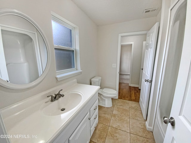 bathroom featuring toilet, vanity with extensive cabinet space, and tile flooring