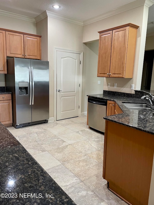 kitchen with dark stone counters, stainless steel appliances, light tile floors, ornamental molding, and sink