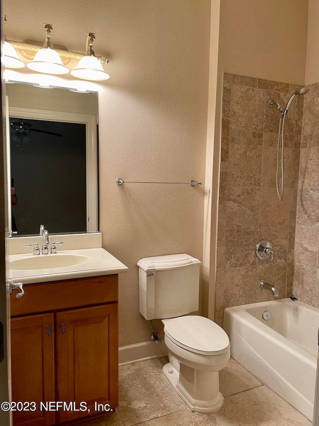 full bathroom with tile floors, tiled shower / bath, vanity, and toilet