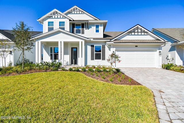 view of front of house featuring a garage, a front lawn, and covered porch