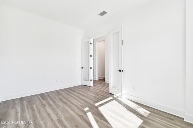 empty room with ornamental molding and light hardwood / wood-style floors