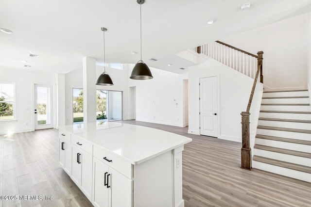 kitchen with pendant lighting, white cabinetry, light hardwood / wood-style floors, and a kitchen island