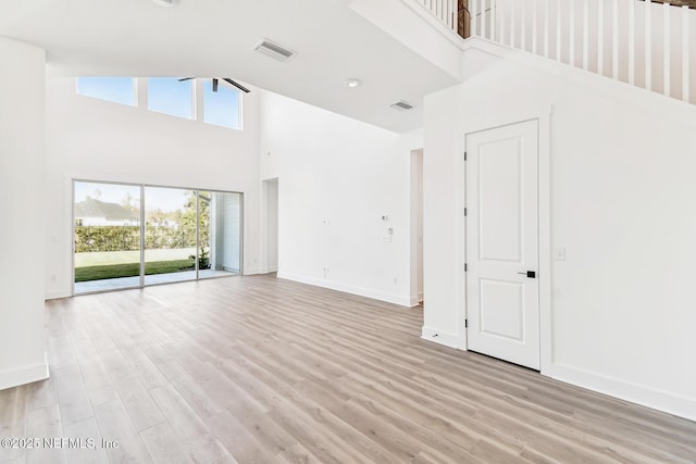 unfurnished living room with high vaulted ceiling and light wood-type flooring