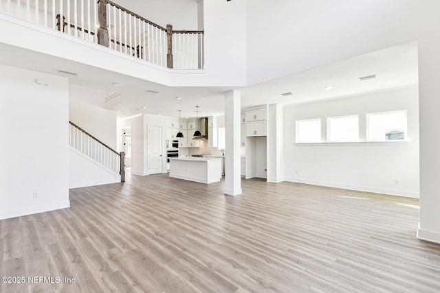 unfurnished living room with a towering ceiling and light hardwood / wood-style floors