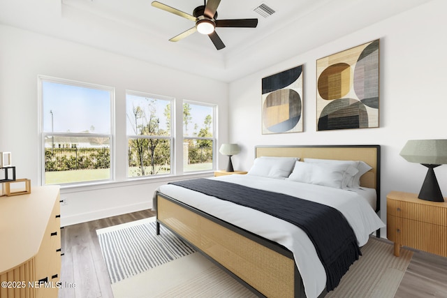 bedroom featuring hardwood / wood-style flooring, ceiling fan, and a tray ceiling