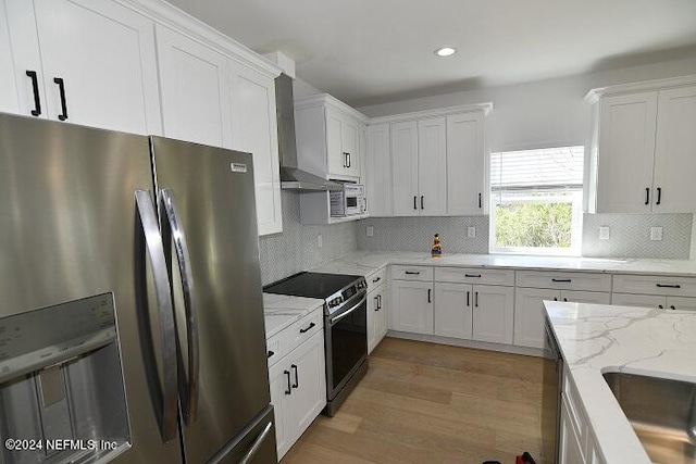 kitchen with white cabinets, appliances with stainless steel finishes, and light hardwood / wood-style floors