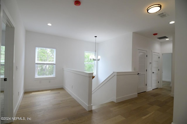 hallway featuring hardwood / wood-style flooring and a notable chandelier